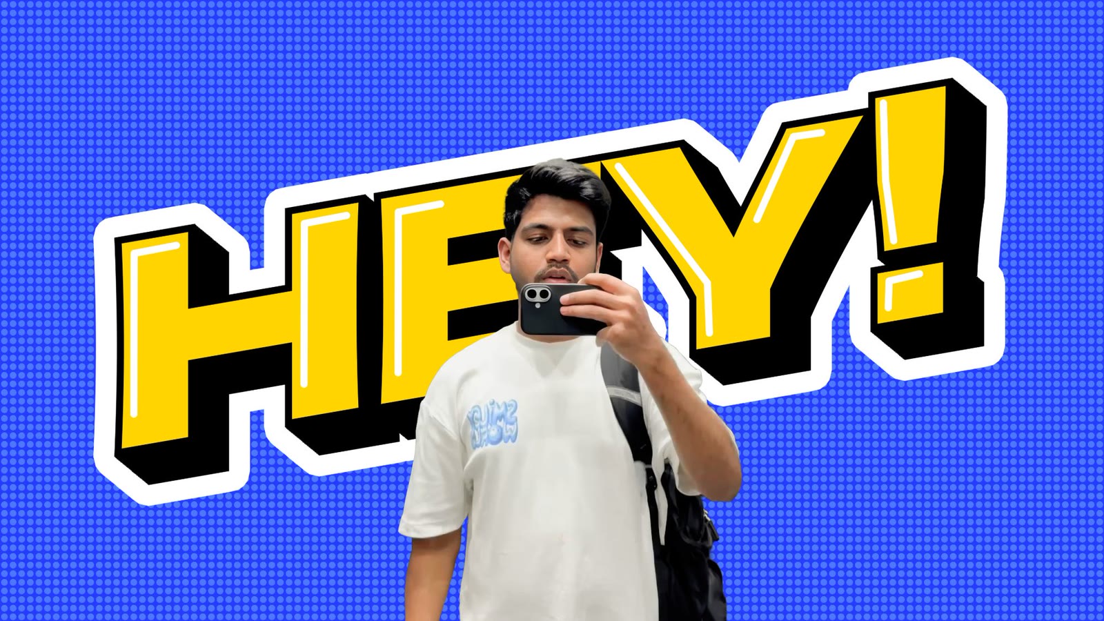 Ashwin Osari taking a mirror selfie in front of a big yellow “HEY!”